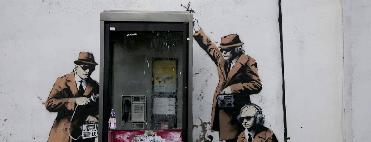 CHELTENHAM, ENGLAND - APRIL 14: A piece of new graffiti street art, claimed to be by the secretive underground guerilla artist Banksy, which appeared on the side of a house in Cheltenham this weekend, is seen on April 14, 2014 in Gloucestershire, England. The artwork, which shows three stencil figures listening into a conversation in an existing telephone box, is just a few miles away from Government Communications Headquaters (GCHQ), which is responsible for providing intelligence and information assurance to the British Government and Armed Forces. (Photo by Matt Cardy/Getty Images)