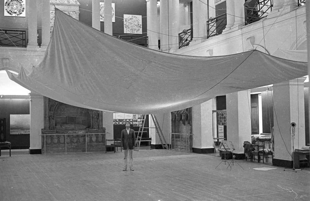 Gunther Uecker sotto la sua scultura presso l'Edinburgh College of Art, con la sua installazione "di stoffa" per la collaborazione con il compositore Friedhelm Dohl a «Sound-Scene» un "concerto" di musica elettronica. Courtesy of Demarco European Art Foundation & Demarco Digital Archive, University of Dundee.